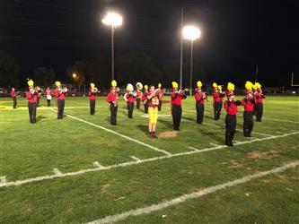 Students in marching band uniforms performing on football field