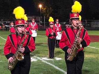 Students in marching band uniforms performing on football field